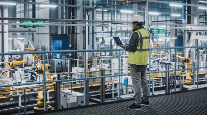 Man stands in automotive manufacturing facility.