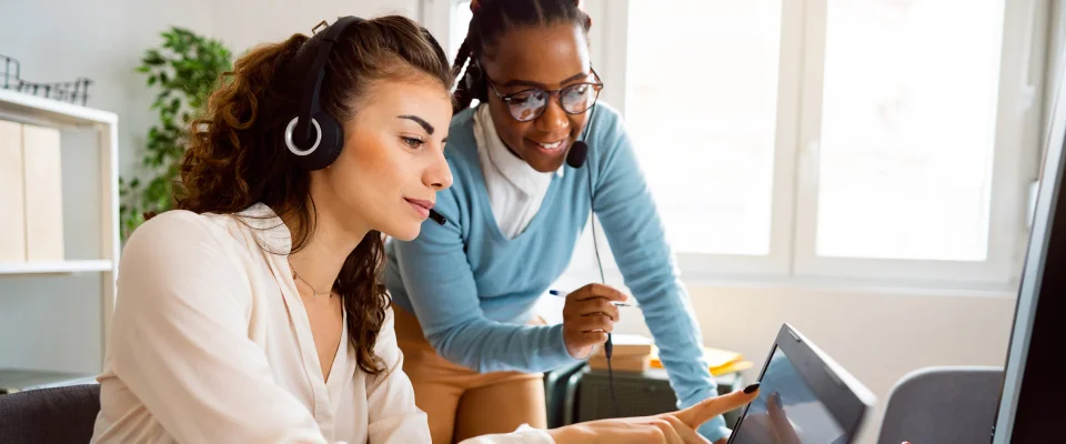 Woman guiding her colleague on job tasks at an inbound call center service.