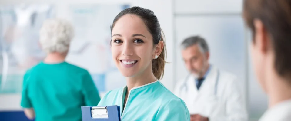 Female nurse holding patient records while smiling in a hospital.