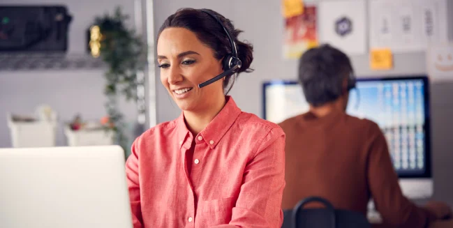 Business Team Wearing Telephone Headsets Talking To Callers In Customer Services Department