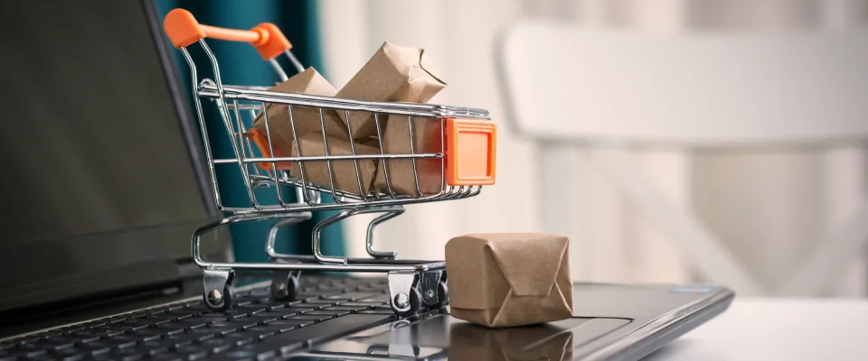 Online shopping concept. Shopping cart, small boxes, laptop on the desk